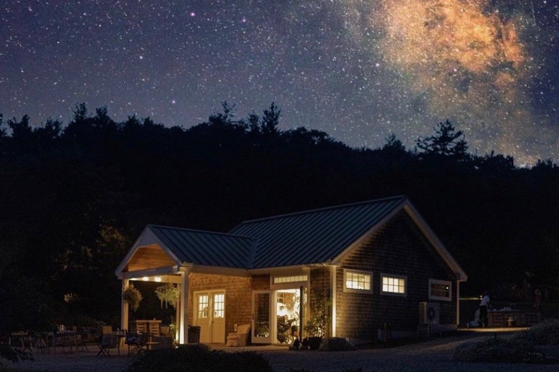 A photo of the Cottage illuminated against the evening sky.